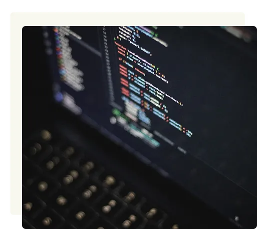 Close-up of a laptop keyboard and screen displaying lines of colorful programming code on a dark background.
