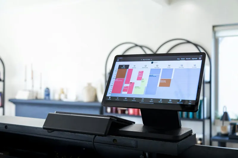 Tablet on a desk stand showing a colorful scheduling dashboard.
